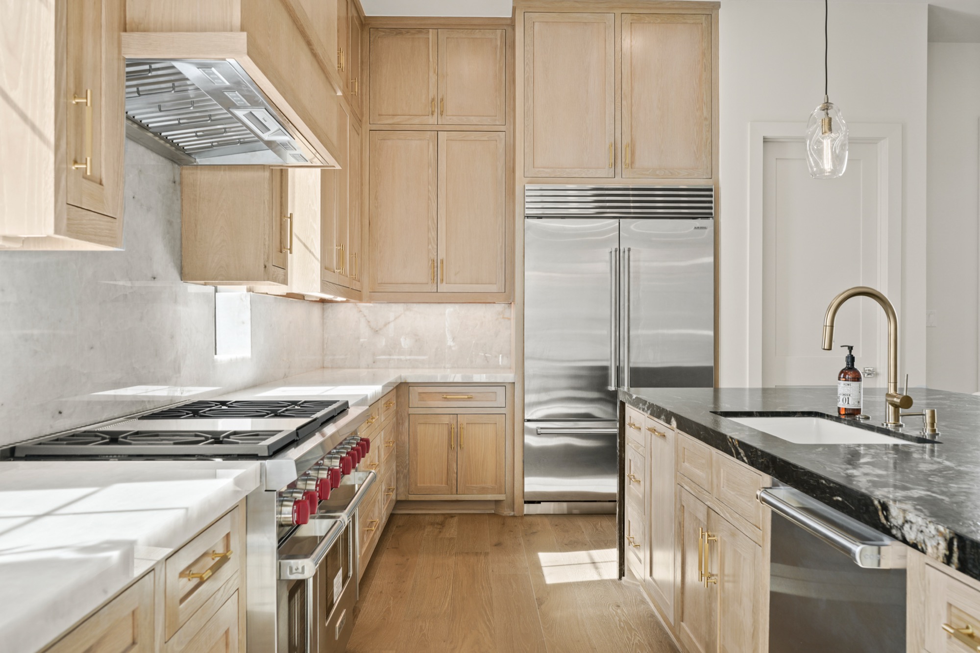Chef's kitchen with professional-grade range, custom cabinetry, and a veined stone island