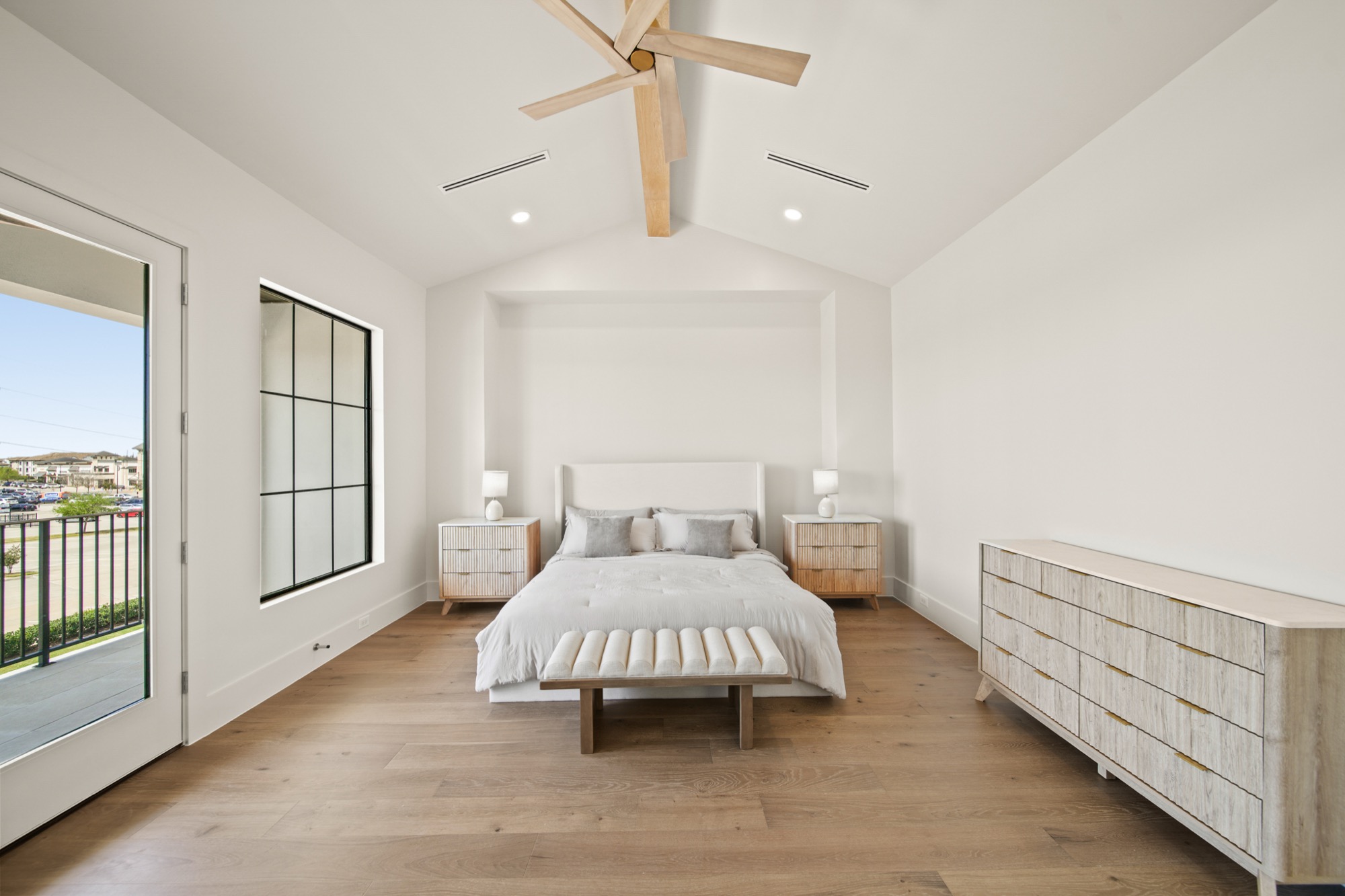Primary suite with vaulted ceiling, lake-view windows, and bespoke millwork